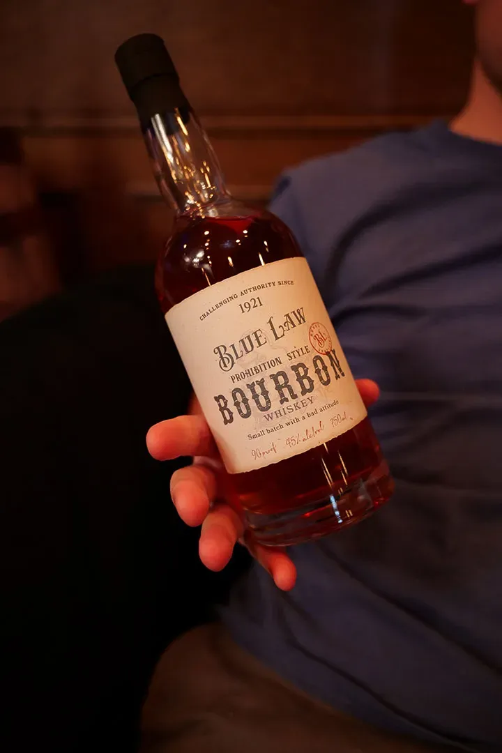 Hand holding blue law bourbon bottle