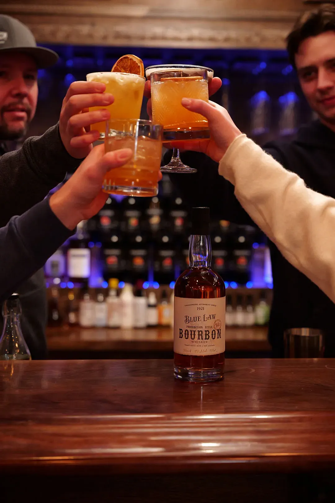Cheers with cocktails over bourbon bottle