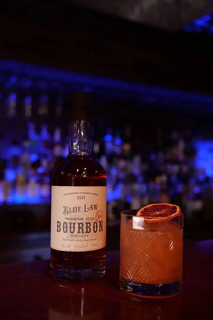 Bourbon bottle with orange slice cocktail